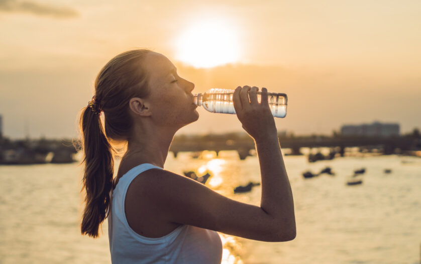 woman drinking water outdoor on sunny day.