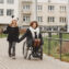 Mother in a wheelchair with her daughter walking outside at park.