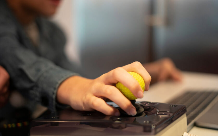 Close up of a kid hand on adaptive mouse using computer