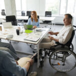 Man in wheelchair having meeting with colleagues in the office