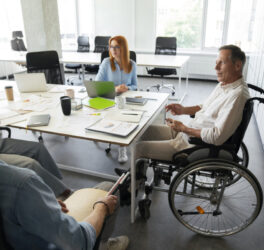 Man in wheelchair having meeting with colleagues in the office
