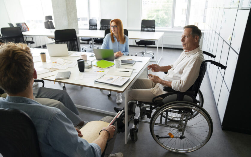Man in wheelchair having meeting with colleagues in the office