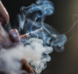 Closeup shot of a person puffing on a cigarette surrounded with smoke