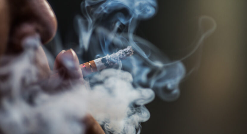 Closeup shot of a person puffing on a cigarette surrounded with smoke