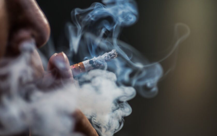 Closeup shot of a person puffing on a cigarette surrounded with smoke