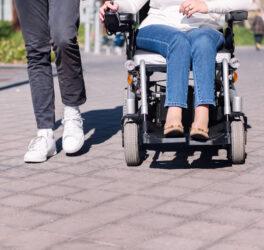 Woman using wheelchair with a man taking a walk
