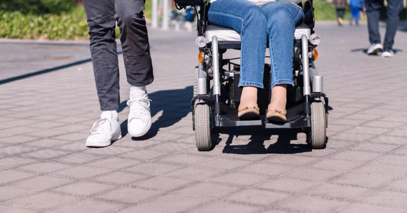 Woman using wheelchair with a man taking a walk