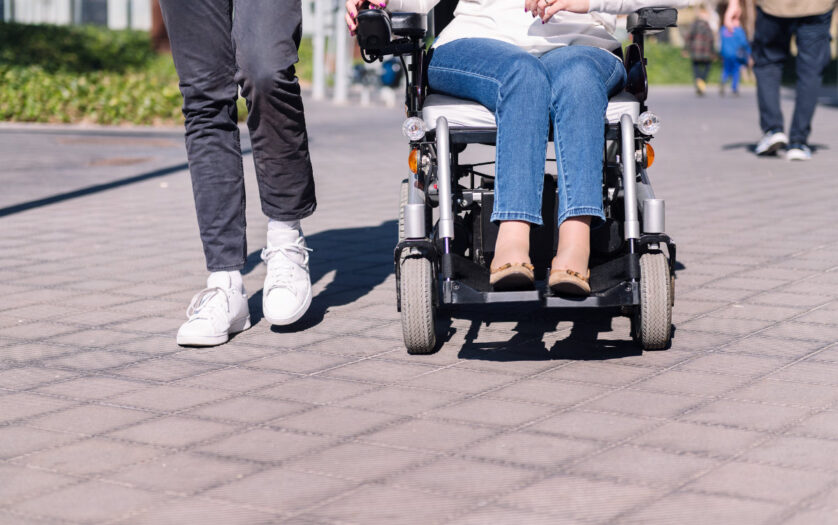 Woman using wheelchair with a man taking a walk