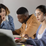 Classmates learning together from laptop and notes