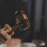 Judge with gavel at wooden table indoors