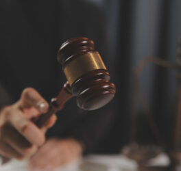 Judge with gavel at wooden table indoors