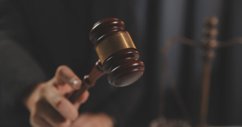 Judge with gavel at wooden table indoors