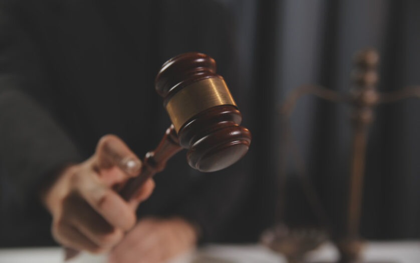 Judge with gavel at wooden table indoors