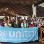 A group of participants from the Pacific stand in front of a UNITAR banner for a group photo