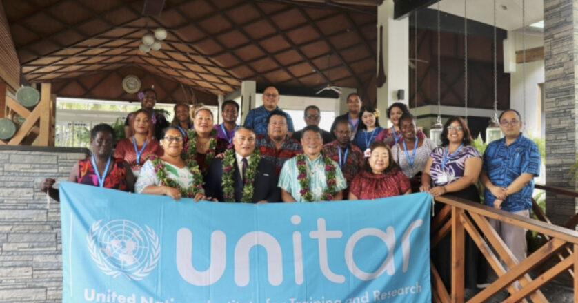 A group of participants from the Pacific stand in front of a UNITAR banner for a group photo