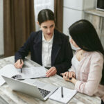 Women Discussing About Paperwork
