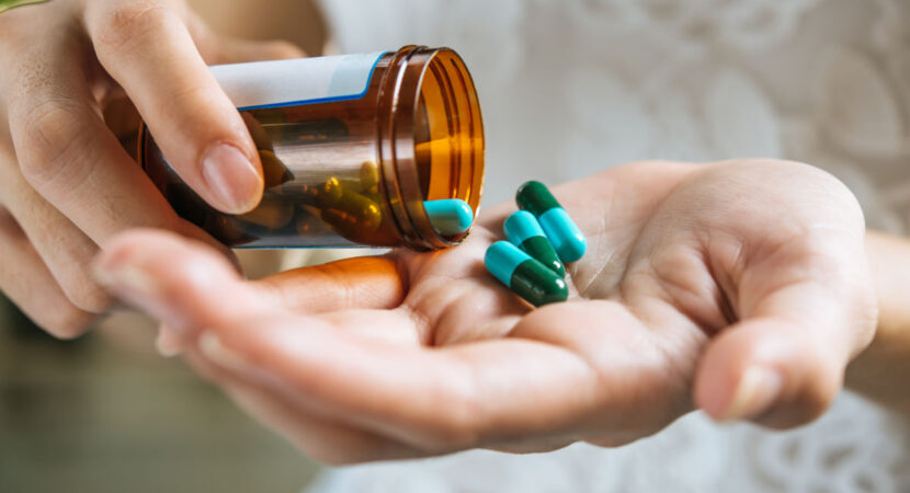 Woman's hand pours the medicine pills out of the bottle