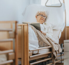 Senior woman lies in bed and reads a book