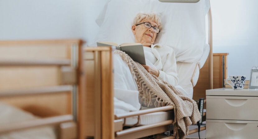 Senior woman lies in bed and reads a book