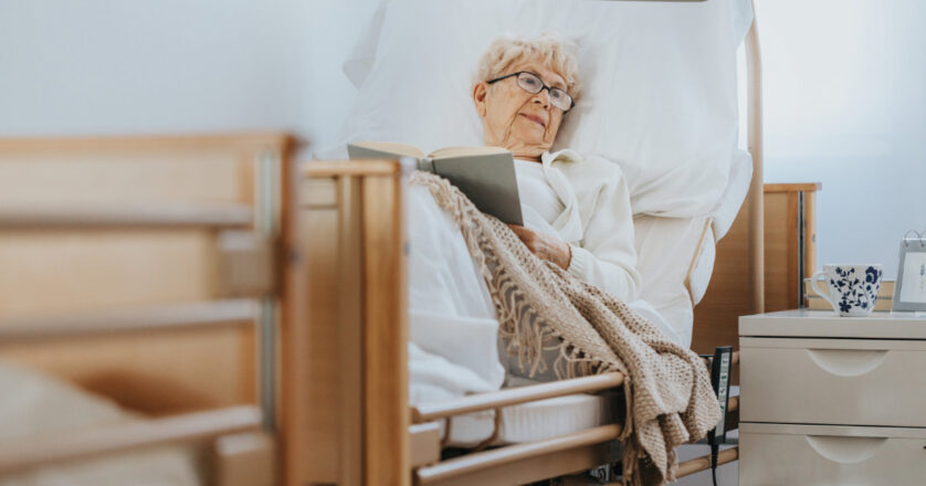 Senior woman lies in bed and reads a book