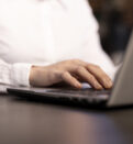 A closeup of a woman typing on her laptop, her fingers swiftly navigating the keyboard as she inputs data.