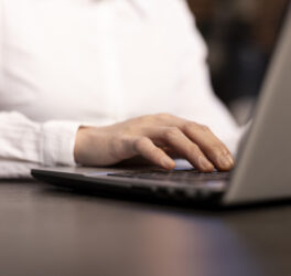 A closeup of a woman typing on her laptop, her fingers swiftly navigating the keyboard as she inputs data.
