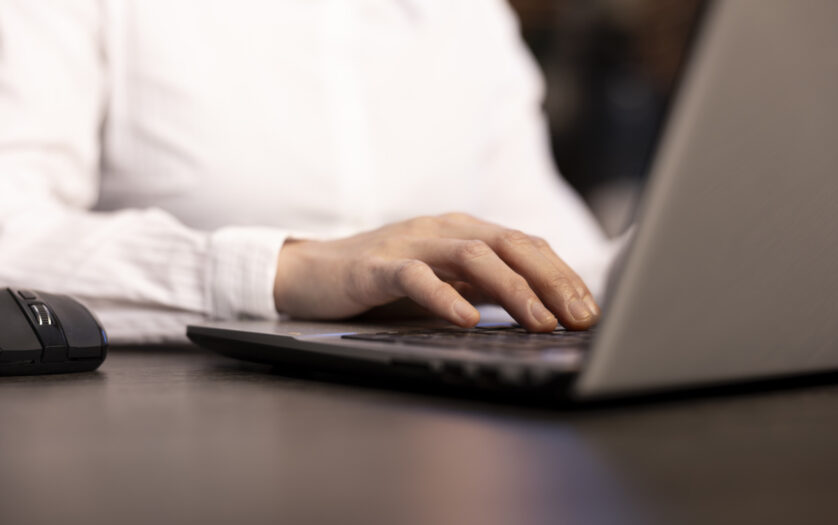 A closeup of a woman typing on her laptop, her fingers swiftly navigating the keyboard as she inputs data.