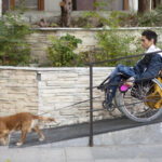 Side view of man in a wheelchair with dog on the ramp