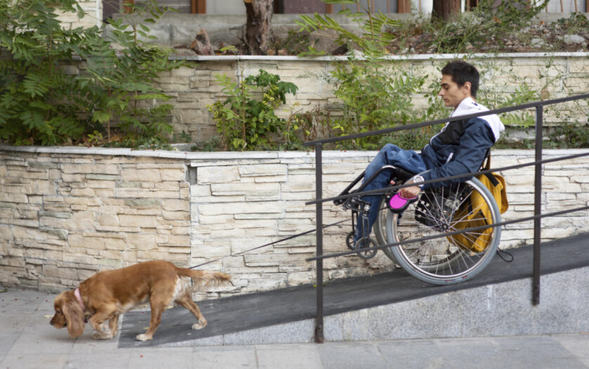 Side view of man in a wheelchair with dog on the ramp