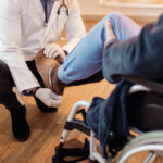 doctor examining leg of senior patient at nursing home