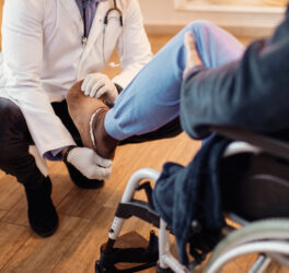 doctor examining leg of senior patient at nursing home