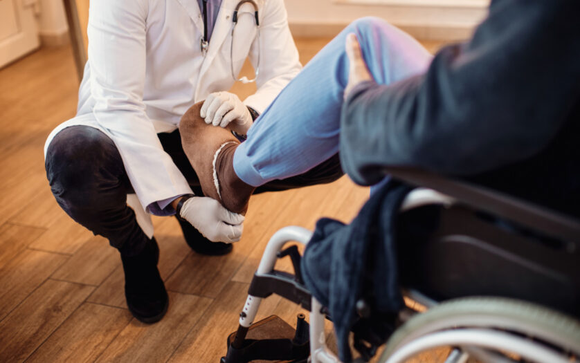 doctor examining leg of senior patient at nursing home