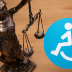 Blindfolded justice holding up the scales with blue disability sign