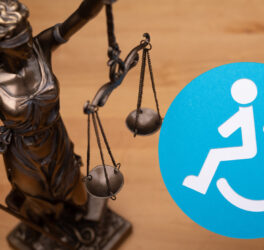 Blindfolded justice holding up the scales with blue disability sign