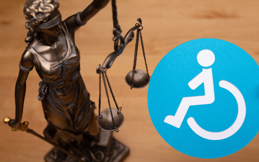 Blindfolded justice holding up the scales with blue disability sign