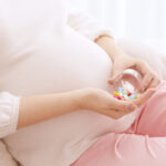 Closeup of pregnant woman holding plastic jar with pills