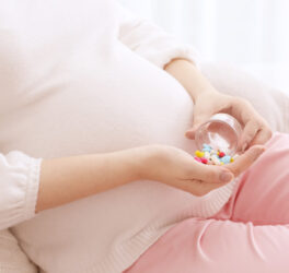 Closeup of pregnant woman holding plastic jar with pills