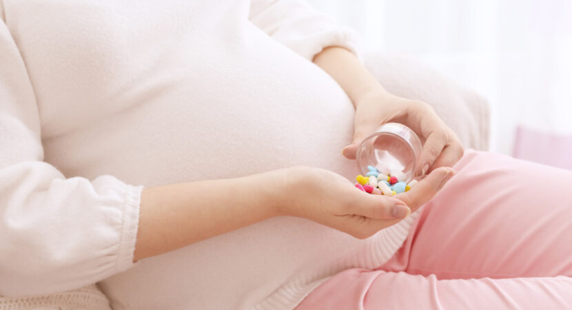 Closeup of pregnant woman holding plastic jar with pills