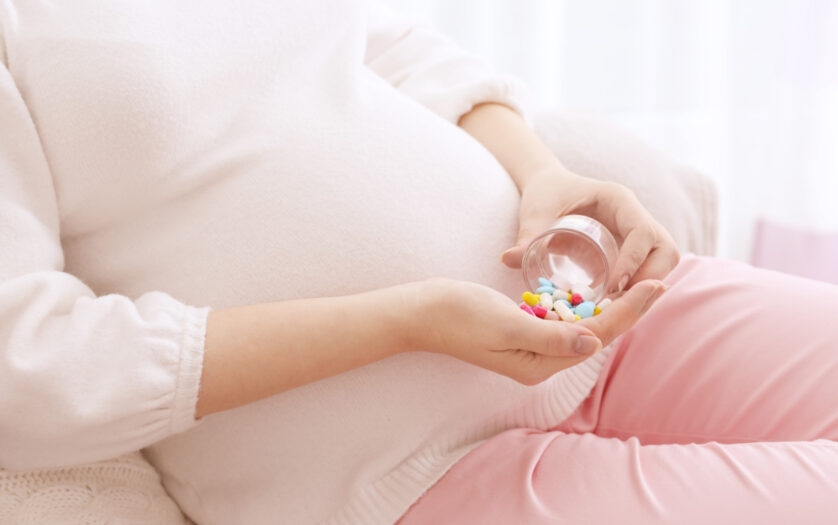 Closeup of pregnant woman holding plastic jar with pills