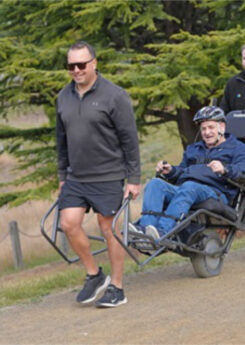 two peoTwo people help push an all-terrain wheelchair across rough terrain