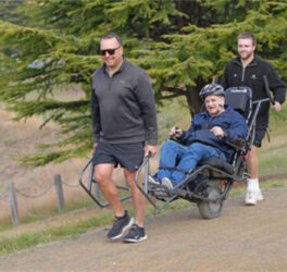 two peoTwo people help push an all-terrain wheelchair across rough terrain