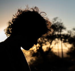 Silhouette of young man with fluffy hair formed by the backlit sun at dusk