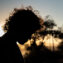 Silhouette of young man with fluffy hair formed by the backlit sun at dusk