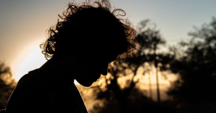 Silhouette of young man with fluffy hair formed by the backlit sun at dusk