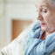 Close-up view of old woman in blue-and-white striped scarf sitting and looking down