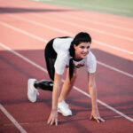 disabled athlete woman with prosthetic leg doing stretching exercises while sitting