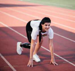 disabled athlete woman with prosthetic leg doing stretching exercises while sitting