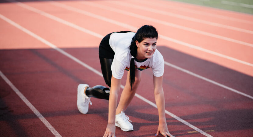 disabled athlete woman with prosthetic leg doing stretching exercises while sitting