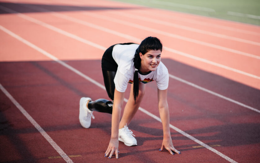 disabled athlete woman with prosthetic leg doing stretching exercises while sitting