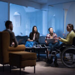 woman in wheelchair with colleagues working in office